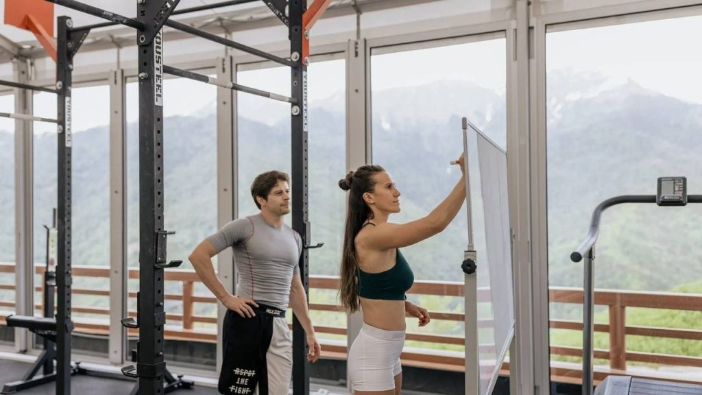 Entrenadora personal explicando un ejercicio como parte de su formación en el gimnasio
