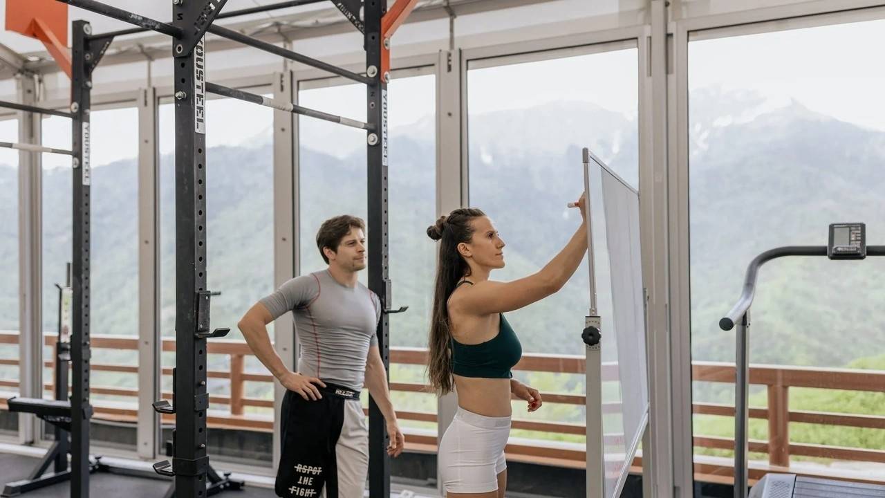 Entrenadora personal explicando un ejercicio como parte de su formación en el gimnasio